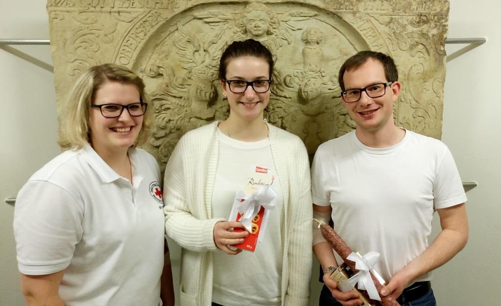 Nina Springub (Erstspenderin) und Björn Hartung (10. Spende) sowie DRK-Schatzwartin Katharina Hartung hinter dem Wappen von Oberst von Koch, Foto: C. Appun.
